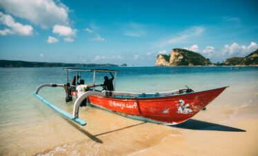 A colorful boat rests on a tranquil Bali beach, capturing the serene and picturesque coastal scenery.
