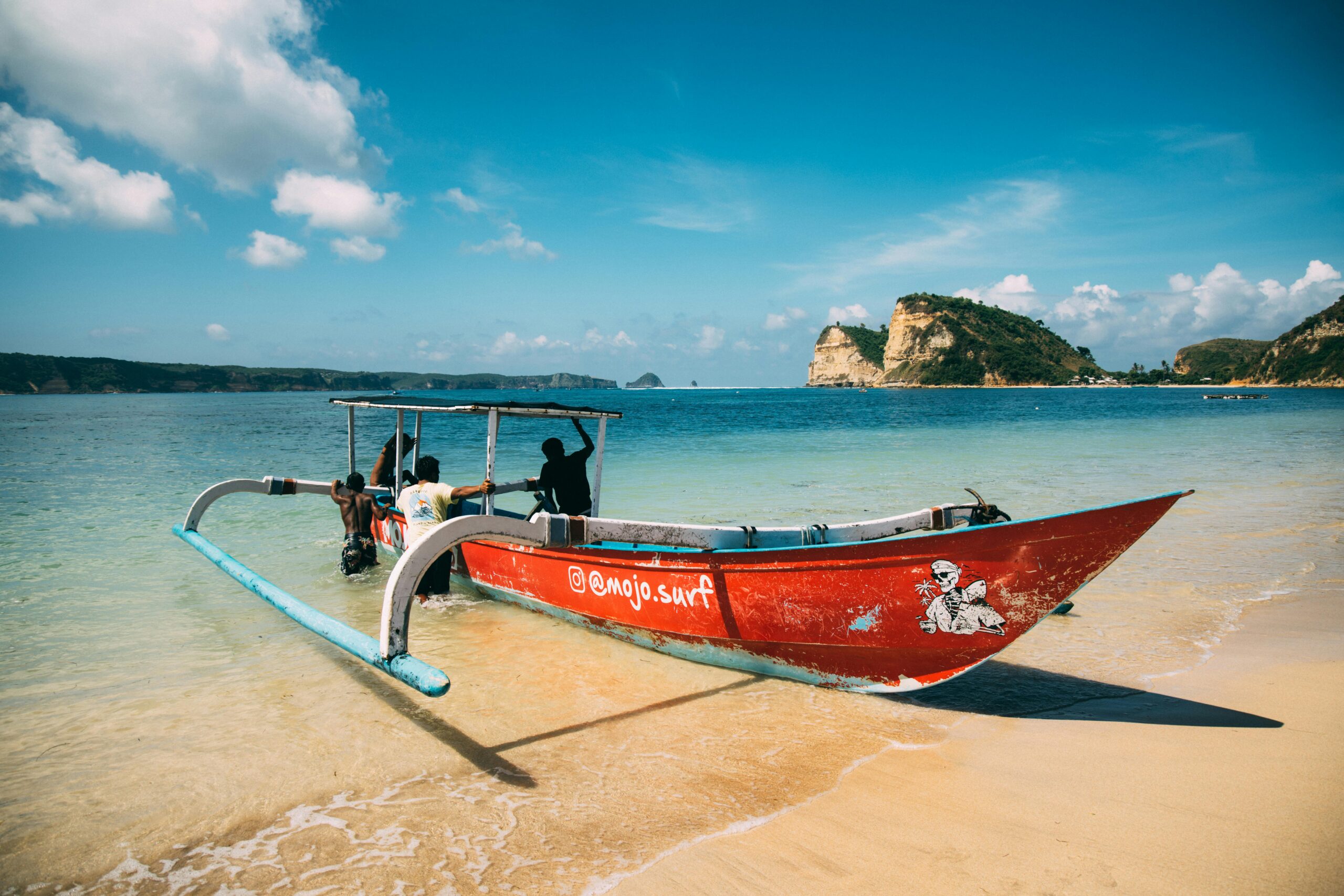 A colorful boat rests on a tranquil Bali beach, capturing the serene and picturesque coastal scenery.