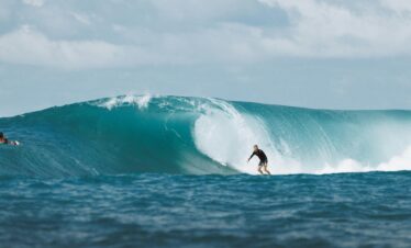 Surfer riding a massive ocean wave in Bali, capturing the thrill and beauty of water sports.