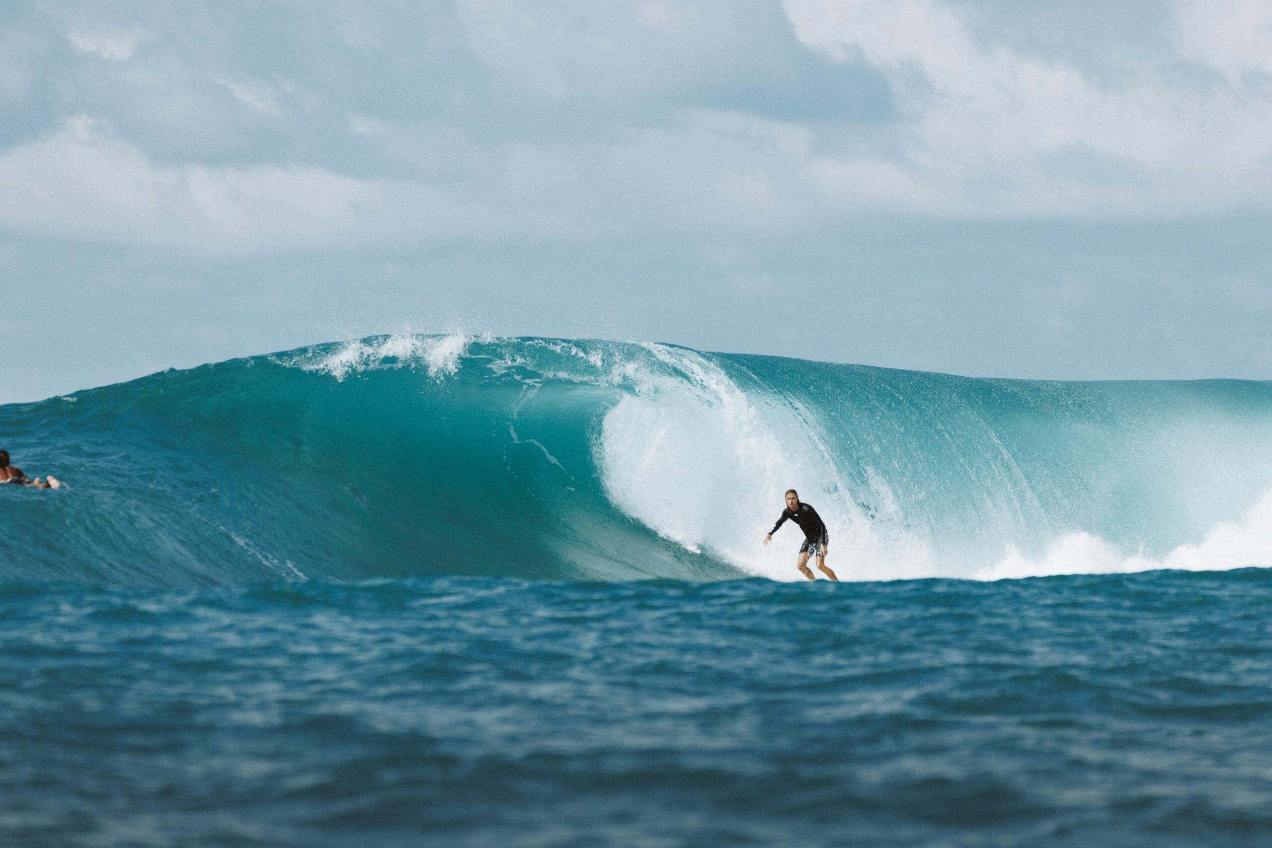 Surfer riding a massive ocean wave in Bali, capturing the thrill and beauty of water sports.