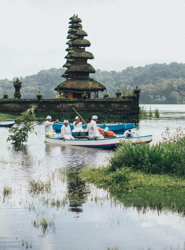 Traditional Balinese temple with boats on a serene lake, capturing cultural and scenic beauty.