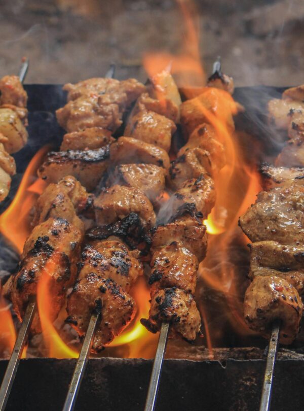 Juicy skewers of grilled meat sizzling over open flames, creating a tasty barbecue feel.