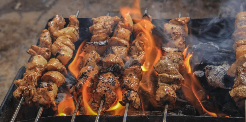 Juicy skewers of grilled meat sizzling over open flames, creating a tasty barbecue feel.