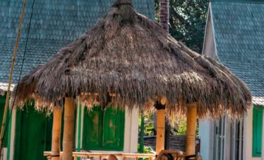 A woman relaxing in a tropical Bali resort hut by the pool surrounded by palm trees.