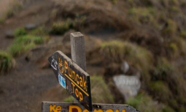 Directional signs on a misty trail leading to Rinjani's summit in Indonesia.