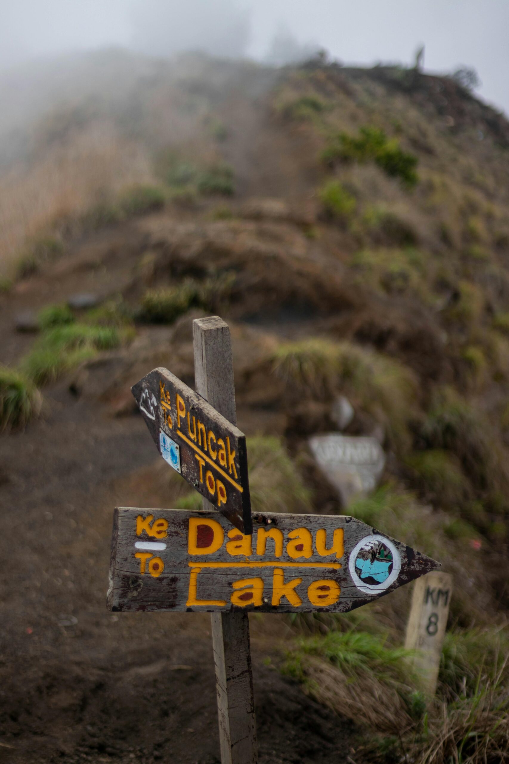 Directional signs on a misty trail leading to Rinjani's summit in Indonesia.