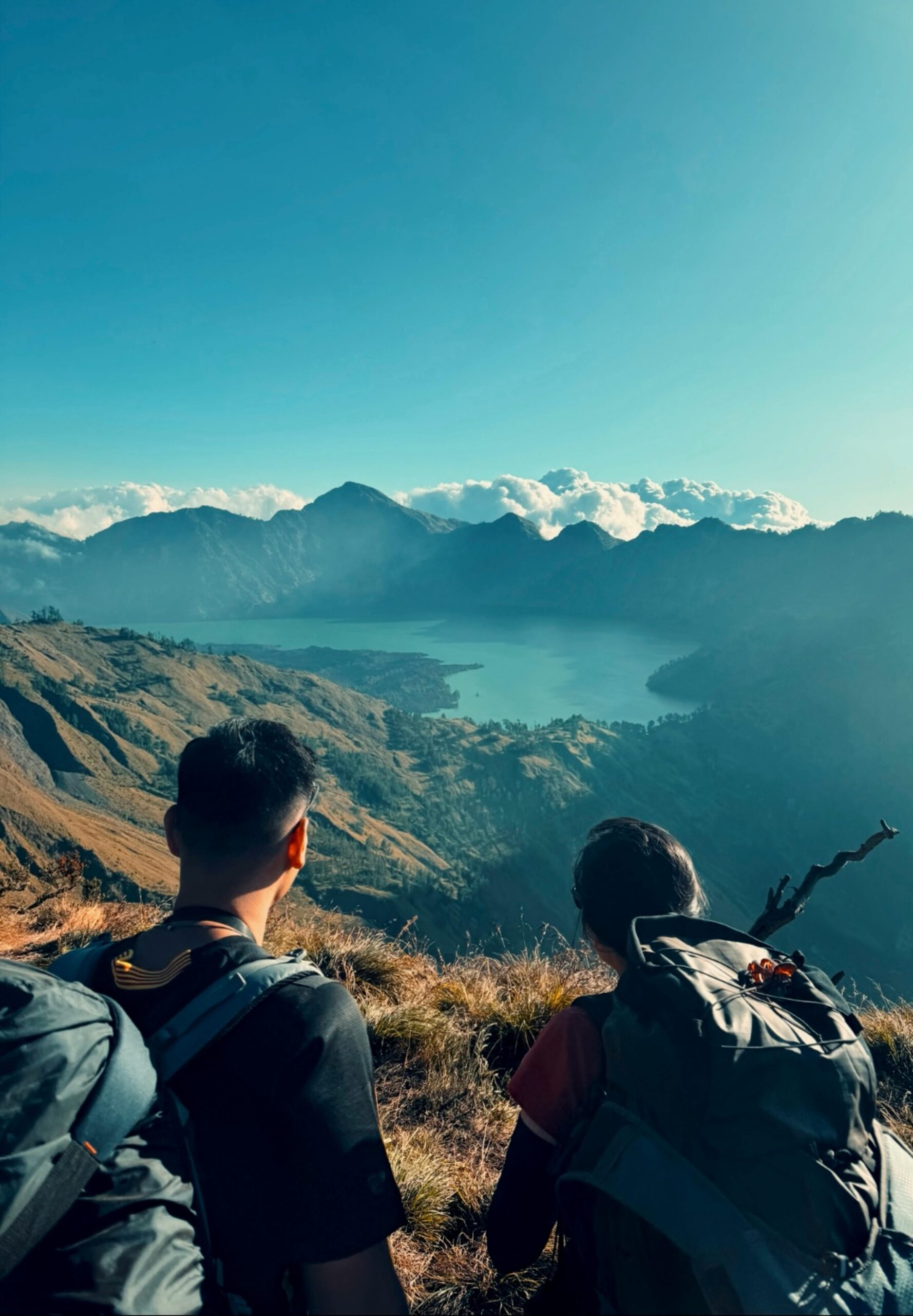 Two hikers enjoy a breathtaking view of Mount Rinjani's crater lake in Indonesia's Nusa Tenggara Barat.